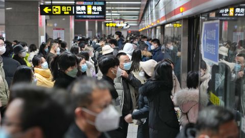 Citizens wearing masks board a subway train on Monday in Henan province's Zhengzhou, where negative Covid-19 test results are no longer required for riding public transport.