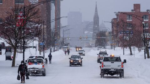 People and vehicles traverse Main St. in Buffalo, on Monday after a massive snowstorm blanketed the city. 