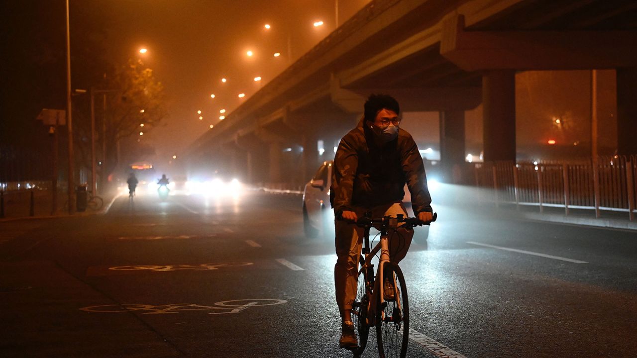 A man rides a bike along a street during a sandstorm in Beijing on April 10, 2023. 