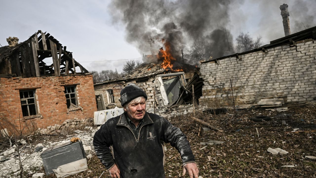 A man stands outside a burning house after shelling in the town of Chasiv Yar, near Bakhmut, on March 21, 2023. 