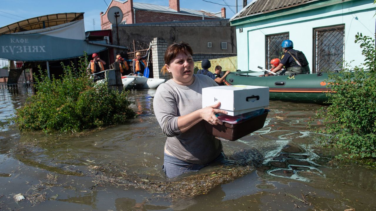 A woman wades through waist-high water after retrieving some belongings from her home in Kherson after the bursting of the Kakhovka dam. 