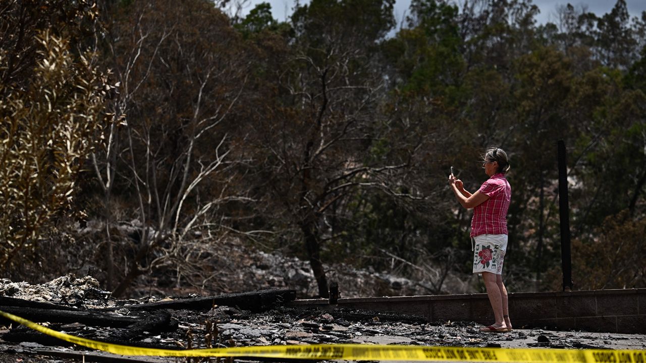 A caretaker photographs the site of a home destroyed by the Maui wildfires in Kula, Hawaii on Sunday.