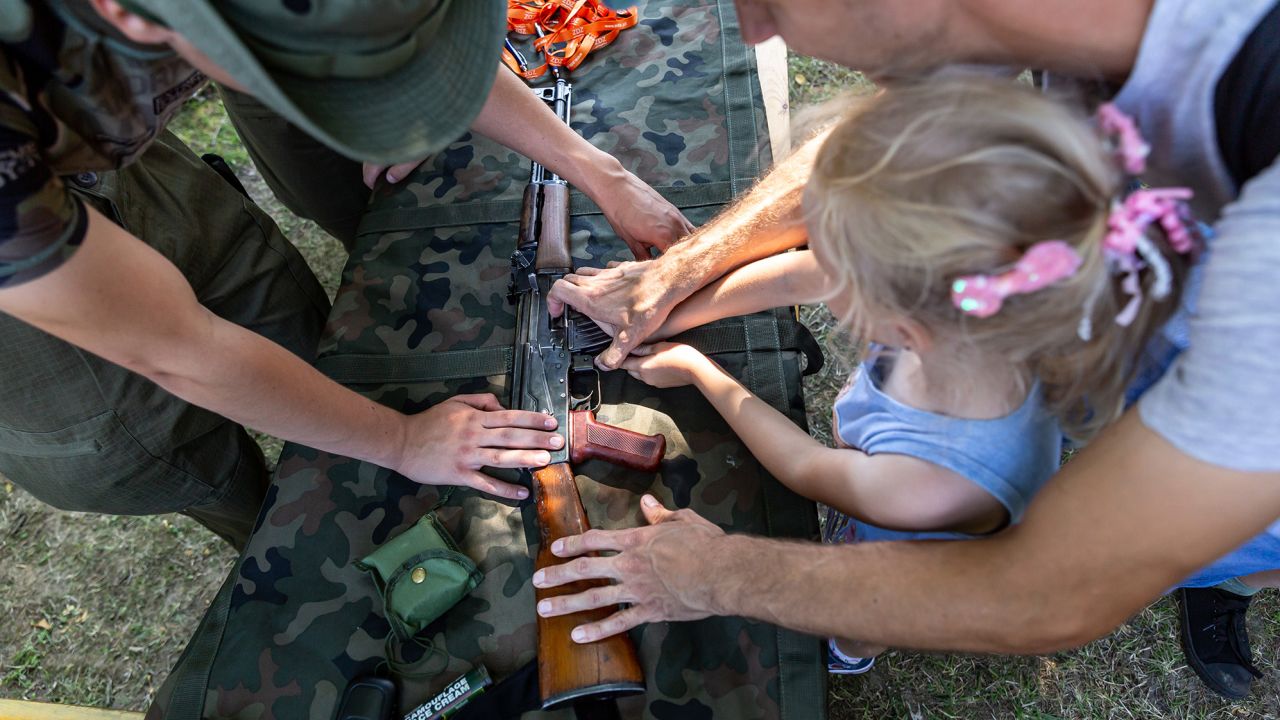 A Polish servicemember shows a weapon to children during a military festival, a part of Polish Army Day celebrations in Polanka Wielka on Sunday.