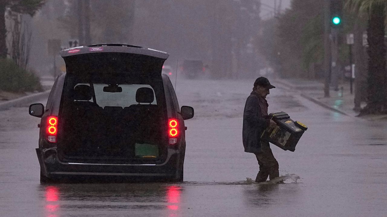 A motorist removes belongings from his vehicle after becoming stuck in a flooded street in Palm Desert, California, on Sunday.