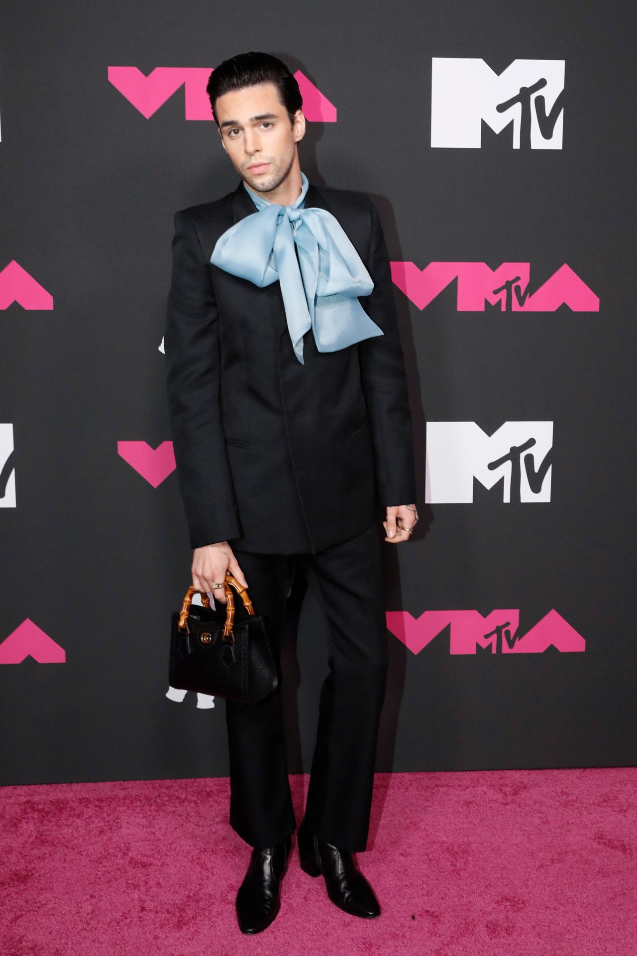 Stephen Sanchez was all wrapped up in a black suit with an oversized baby-blue bow, a black Gucci bamboo handle Diana tote bag and black leather boots. 