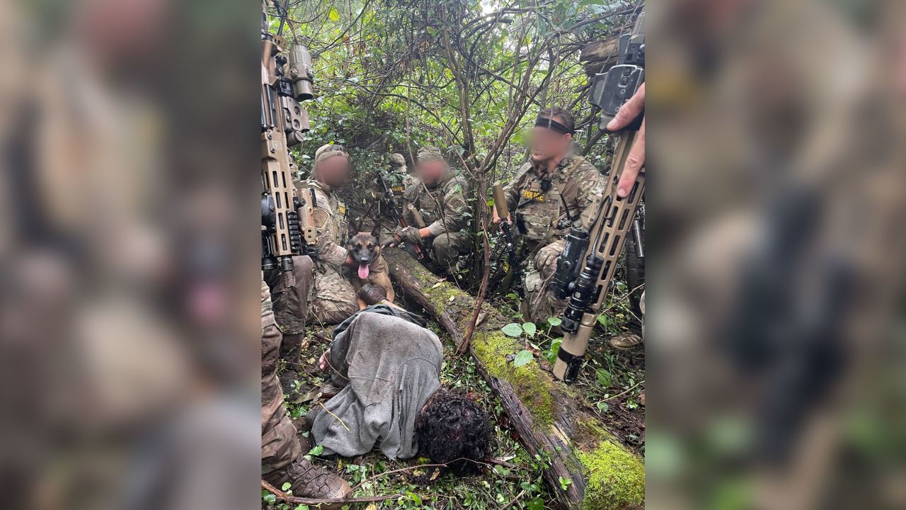 Danilo Cavalcante is seen lying in the woods surrounded by officers and Yoda, a US Border Patrol BORTAC K9, on Wednesday.