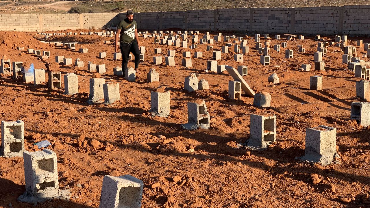 A man walks by the graves of flash flood victims in Derna.