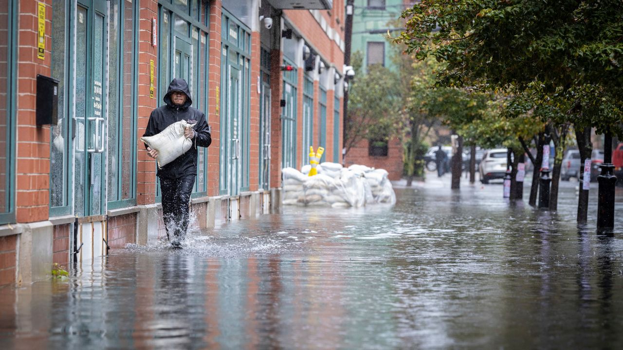 A person carries sandbags on a flooded sidewalk in Hoboken, New Jersey, on Friday.