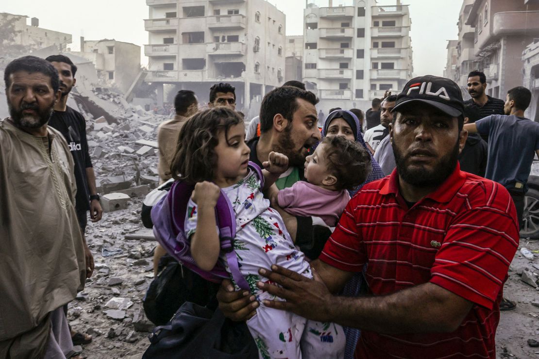 People carry children as they flee, following an Israeli strike on Rafah in the southern Gaza Strip on October 15.