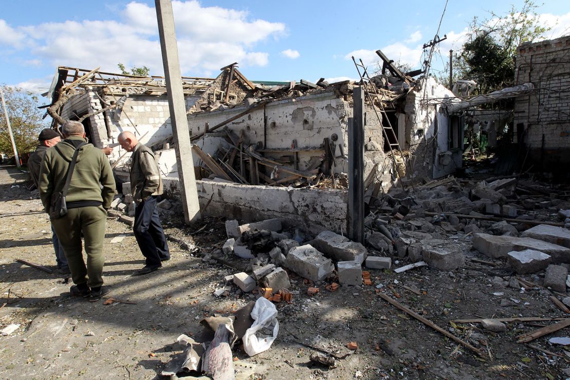 Men stand outside a house destroyed in the Russian rocket attack that took place Wednesday morning, October 18, Obukhivka, Dnipropetrovsk Region, central Ukraine.
