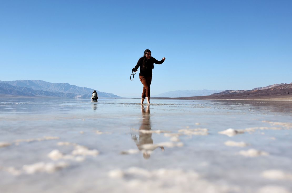 A visitor walks in the sprawling temporary lake at Badwater Basin salt flats in Death Valley National Park on October 21, 2023.